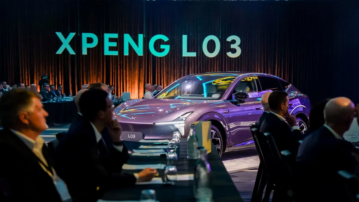 A purple Xpeng L03 SUV displayed among seated guests beneath illuminated XPENG L03 lettering.
